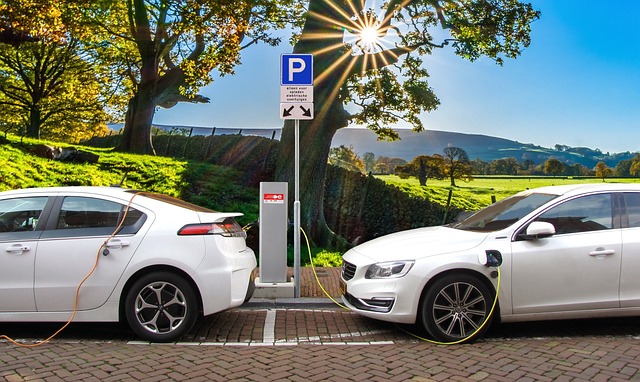 Two white electrical cars being filled up at a charging station