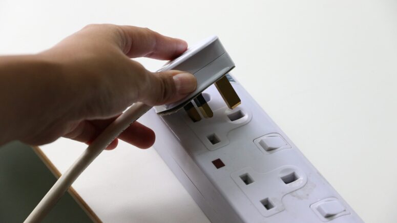 Someone putting a plug in a socket
