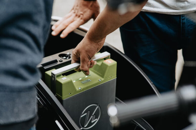 A battery storage system is moved from one place to another. The green battery pack is clearly visible.