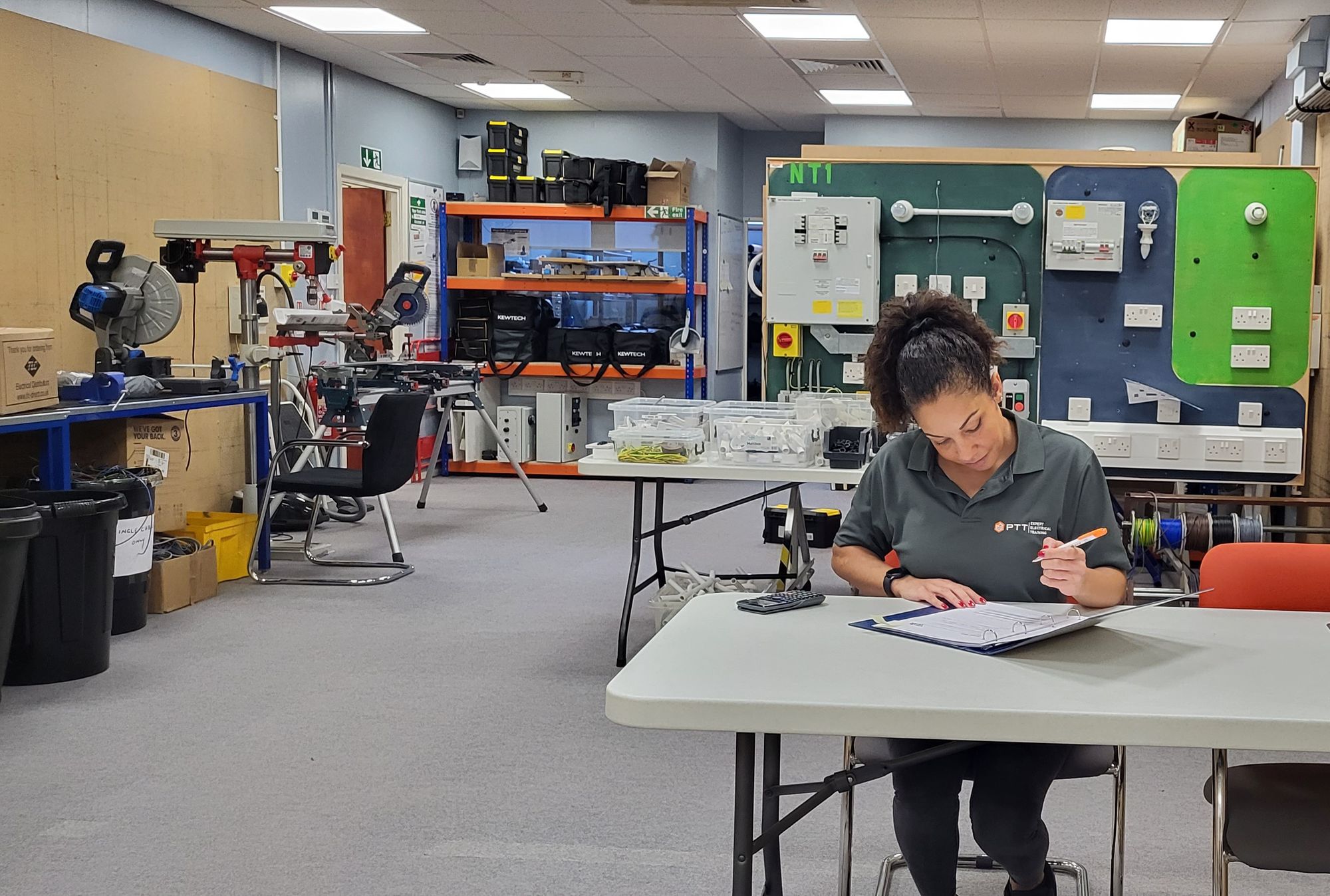 A woman sitting in a training centre upskilling her role as a self employed electrician to help further her career.