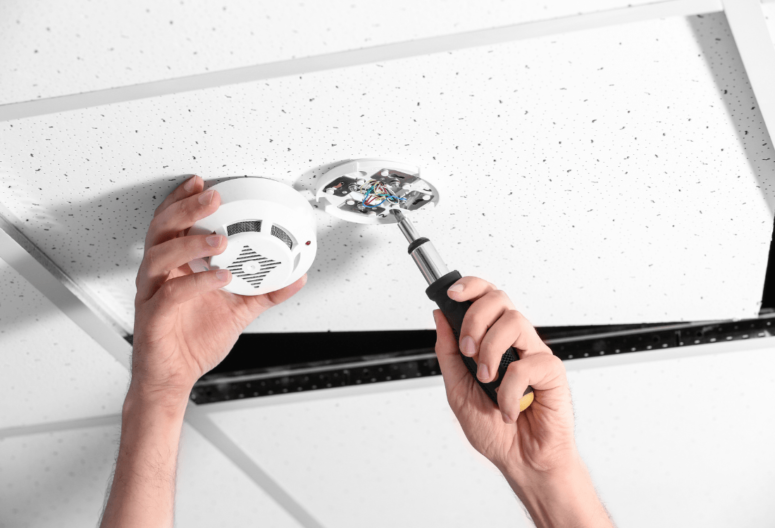 A qualified electrician carefully installing a fire alarm system after taking the Fire Alarm Systems (EAL Level 3) course.